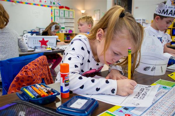 girl dressed as dalmatian dog writing on paper